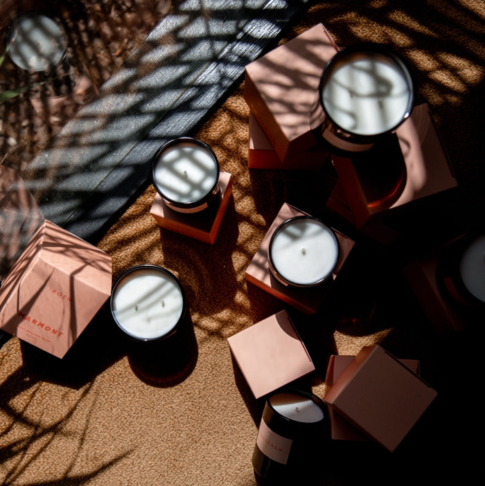 Roen candles with decorative boxes on a textured surface with shadows